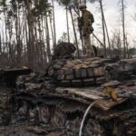 Tentara Ukraina berdiri di atas salah satu tank Rusia yang hancur di pinggiran Kiev