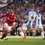 emain Manchester United Cristiano Ronaldo, kiri, menendang bola ketika pemain Brighton Adam Webster mencoba menghentikannya selama pertandingan sepak bola Liga Premier Inggris antara Manchester United dan Brighton di stadion Old Trafford di Manchester, Inggris, Ahad, 7 Agustus 2022.