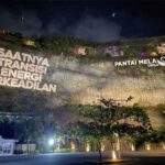 Greenpeace menggelar aksi damai kreatif dengan memproyeksikan pesan berbunyi “Saatnya Transisi Energi Berkeadilan” di Pantai Melasti, Bali, pada Senin petang, 14 November 2022.