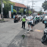 Polisi anggota Satlantas Polres Badung membantu menyeberangkan seorang wisatawan di Jalan Jl. Raya Batubelig – Petitenget Kelurahan Kerobokan Kelod Kecamatan Kuta Utara Kabupaten Badung.