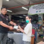 Kelapa Bagian Kebersihan dan Keamanan Perumda Pasar Sewakadarma I Nyoman Swastika meyerahkan buku tabungan kepada penabung sampah di Pasar Badung. (Foto: M-011)